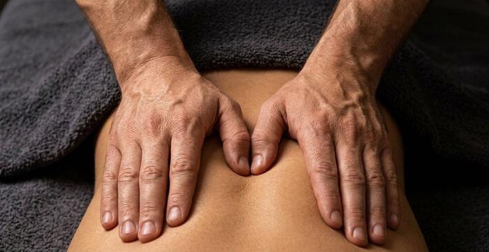 Therapist performing deep tissue massage on a client's lower back at Secret of Health in Buford, GA